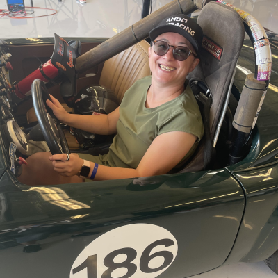 Picture of Asya, a person with a hat sitting in a fancy race car.